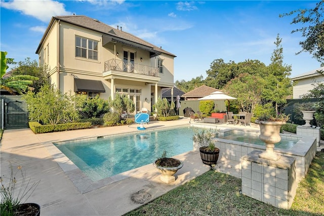 rear view of property with a fenced in pool, a balcony, and a patio area