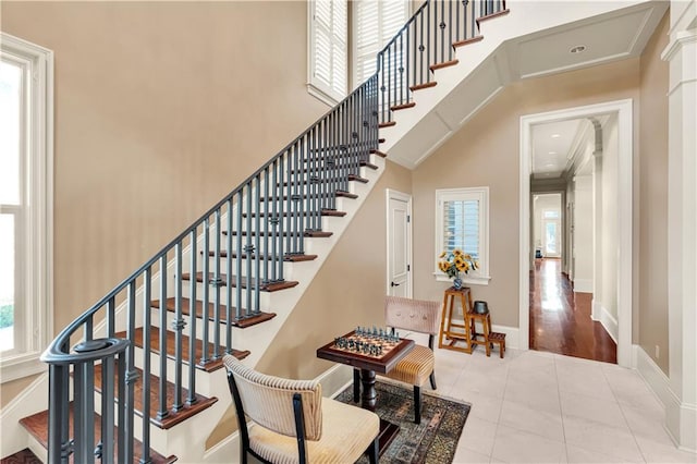 stairway with a high ceiling, wood-type flooring, and crown molding