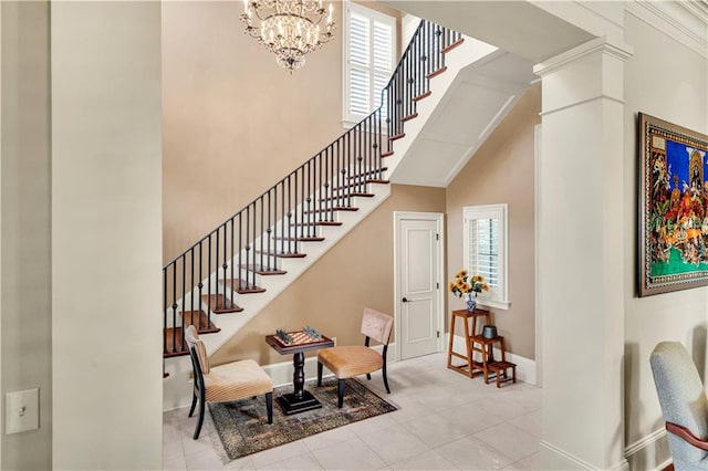 staircase featuring a high ceiling, decorative columns, tile patterned flooring, and a notable chandelier