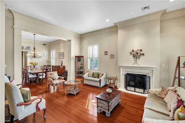 living room with wood-type flooring, crown molding, and an inviting chandelier