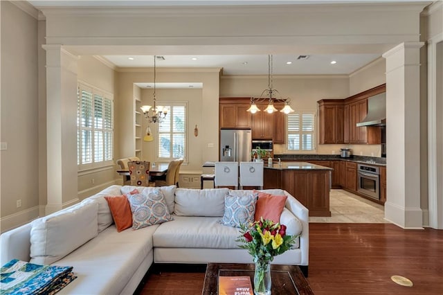 living room with ornamental molding, light wood-type flooring, a notable chandelier, and decorative columns