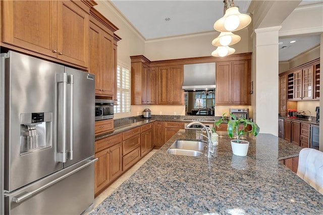 kitchen featuring ornate columns, stainless steel appliances, hanging light fixtures, sink, and ornamental molding