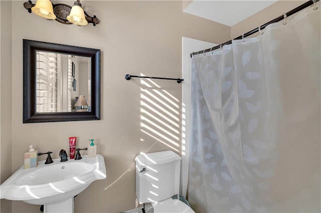 bathroom with walk in shower, sink, and toilet