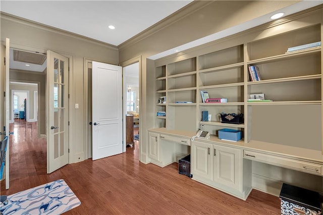 home office featuring ornamental molding, wood-type flooring, and built in desk