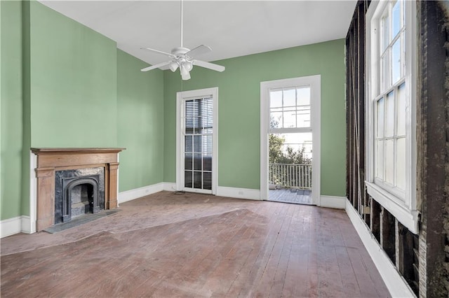 unfurnished living room featuring a premium fireplace, hardwood / wood-style floors, and ceiling fan