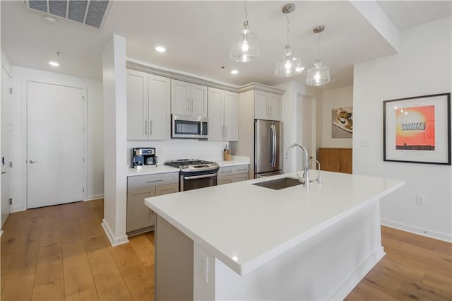 kitchen with visible vents, a sink, stainless steel appliances, light countertops, and light wood-type flooring