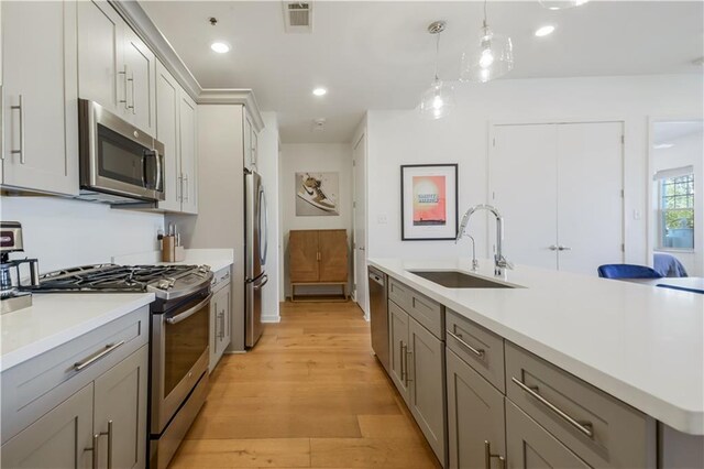 kitchen featuring visible vents, gray cabinetry, light wood-style flooring, appliances with stainless steel finishes, and a sink