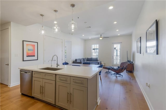 kitchen featuring a sink, dishwasher, light wood-style flooring, and light countertops