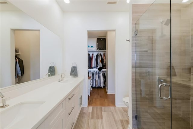 bathroom featuring a shower stall, toilet, wood finished floors, and a sink