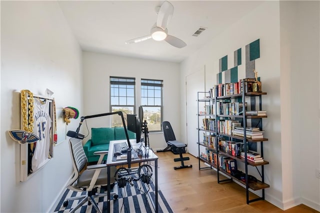 office space featuring visible vents, baseboards, ceiling fan, and wood finished floors