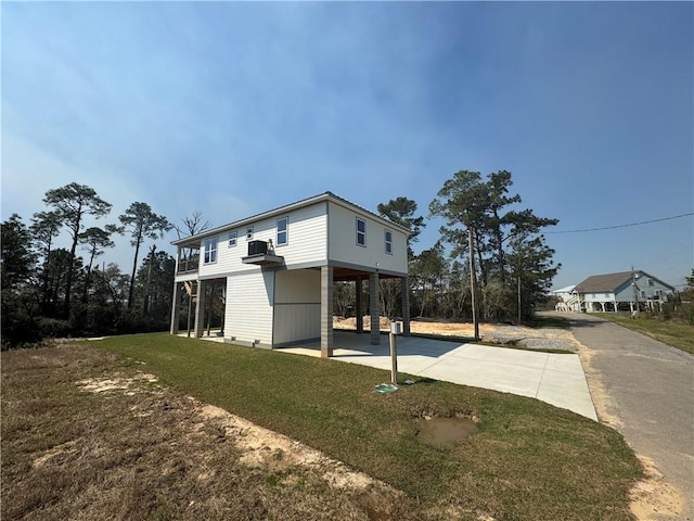 view of property exterior with a carport, concrete driveway, and a yard