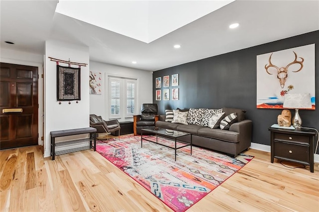 living room featuring hardwood / wood-style flooring and a skylight