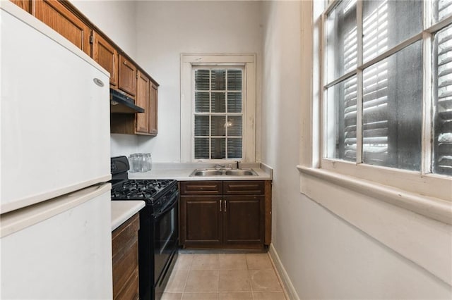 1135 Ursulines Ave, New Orleans, LA 70116 - kitchen with sink, black range oven, white fridge, and light tile patterned floors