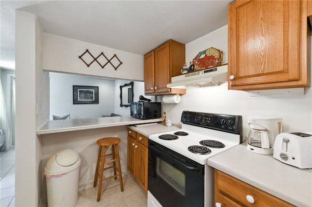 1135 Ursulines Ave, New Orleans, LA 70116 - kitchen featuring light tile patterned floors, electric range, and kitchen peninsula