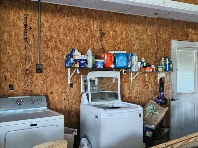 laundry area featuring wooden walls and washer and clothes dryer