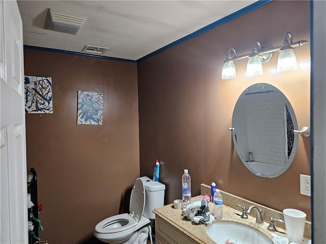 bathroom with vanity, crown molding, a textured ceiling, and toilet