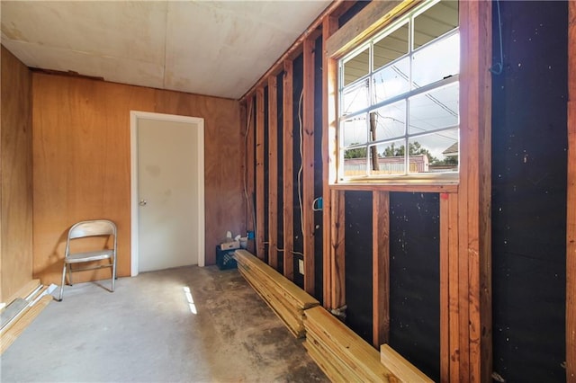 misc room featuring concrete flooring and wood walls