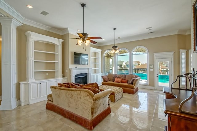 tiled living room featuring ornate columns, ceiling fan, crown molding, and built in features