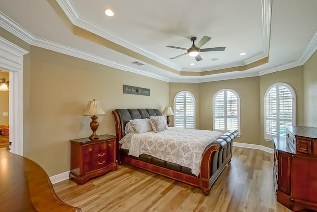 bedroom featuring crown molding, light hardwood / wood-style flooring, a tray ceiling, and ceiling fan