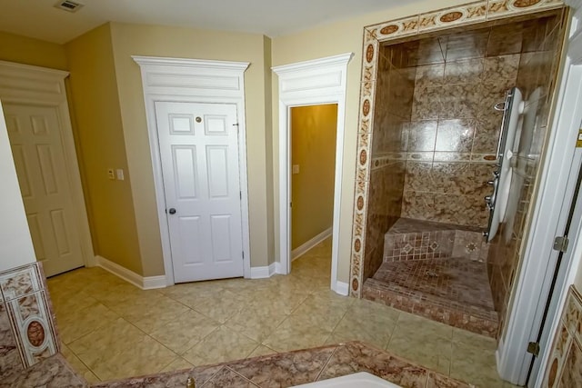 bathroom featuring tiled shower and tile patterned flooring