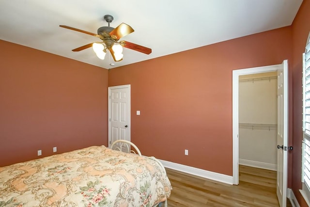 bedroom with a closet, hardwood / wood-style floors, a spacious closet, and ceiling fan