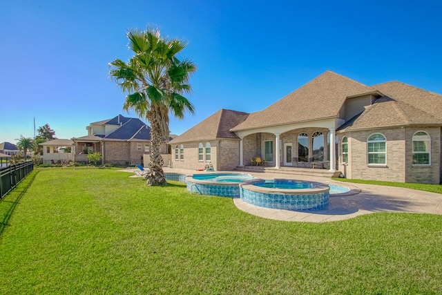 exterior space featuring a patio, a lawn, and a pool with hot tub