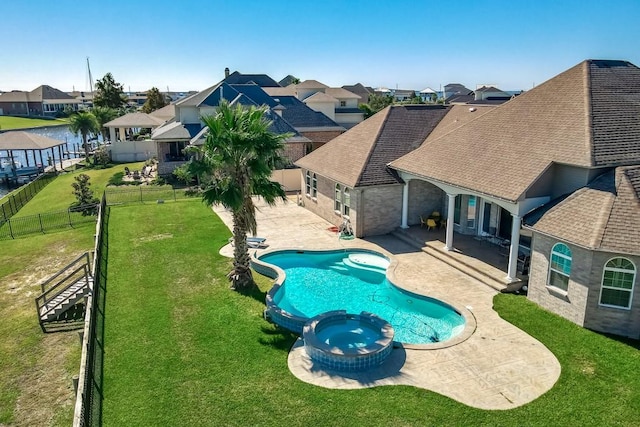 view of swimming pool with a patio area, a yard, an in ground hot tub, and a water view