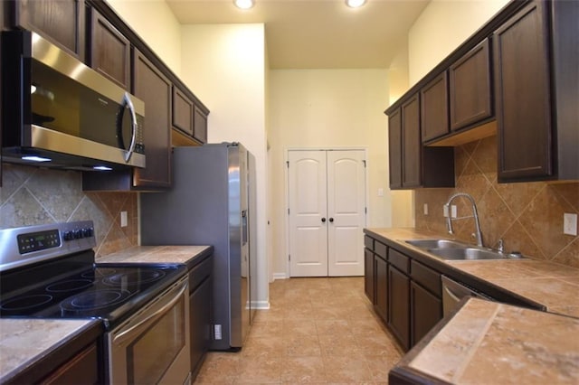 kitchen featuring appliances with stainless steel finishes, decorative backsplash, dark brown cabinetry, and sink