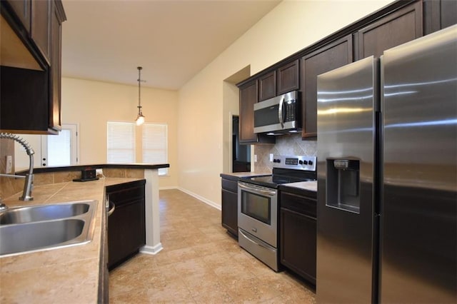 kitchen featuring tasteful backsplash, stainless steel appliances, sink, dark brown cabinetry, and decorative light fixtures