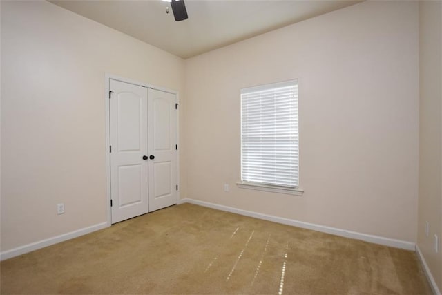 unfurnished bedroom with light colored carpet, a closet, and ceiling fan