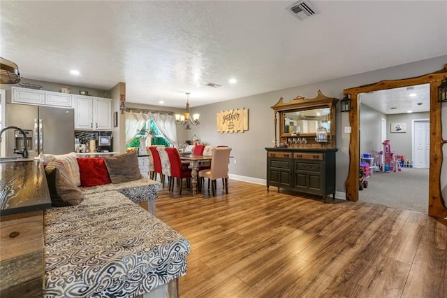 dining room featuring an inviting chandelier, sink, and light hardwood / wood-style floors