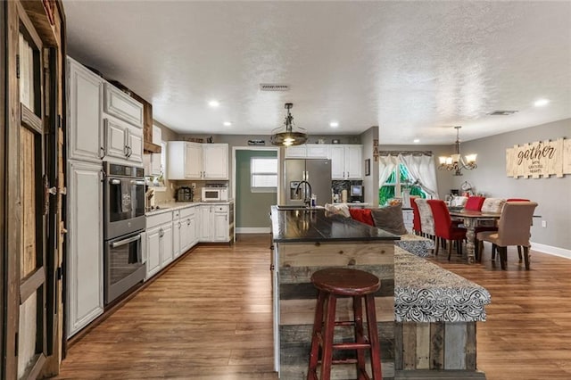 kitchen featuring appliances with stainless steel finishes, a breakfast bar, white cabinetry, and wood-type flooring