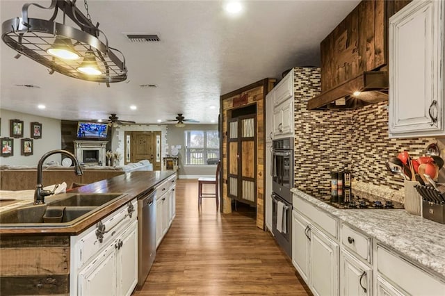 kitchen featuring wood-type flooring, sink, stainless steel dishwasher, white cabinetry, and ceiling fan