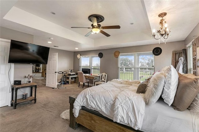 bedroom featuring light colored carpet, a tray ceiling, and ceiling fan with notable chandelier