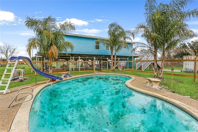 view of pool with a water slide, a playground, and a yard