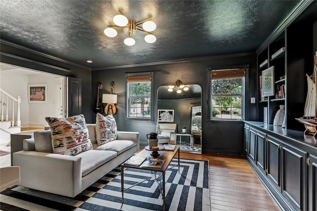 living room with hardwood / wood-style flooring, a textured ceiling, stairs, and crown molding