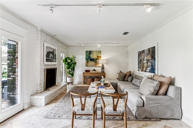living room with crown molding, light tile patterned floors, track lighting, a fireplace, and visible vents