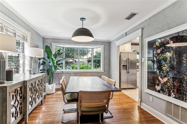 dining room with baseboards, ornamental molding, wood finished floors, and visible vents