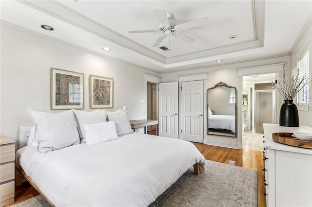 bedroom featuring crown molding, light wood-style floors, ceiling fan, a tray ceiling, and recessed lighting