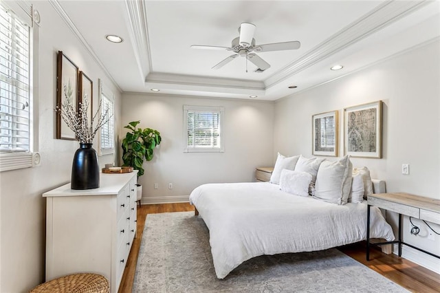 bedroom featuring recessed lighting, a tray ceiling, crown molding, light wood-style flooring, and ceiling fan