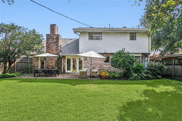 back of property featuring a chimney, a lawn, a fenced backyard, a patio, and brick siding