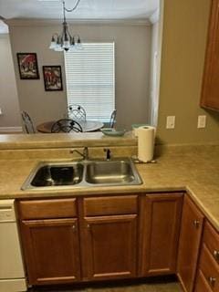 kitchen with a notable chandelier, a sink, light countertops, dishwasher, and crown molding