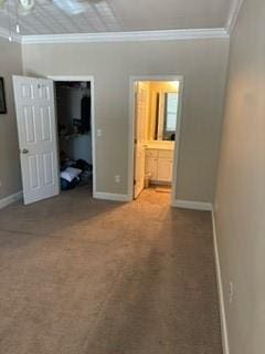 unfurnished bedroom featuring a walk in closet, crown molding, and baseboards