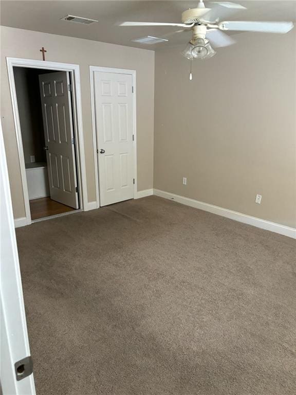 spare room featuring visible vents, dark carpet, ceiling fan, and baseboards