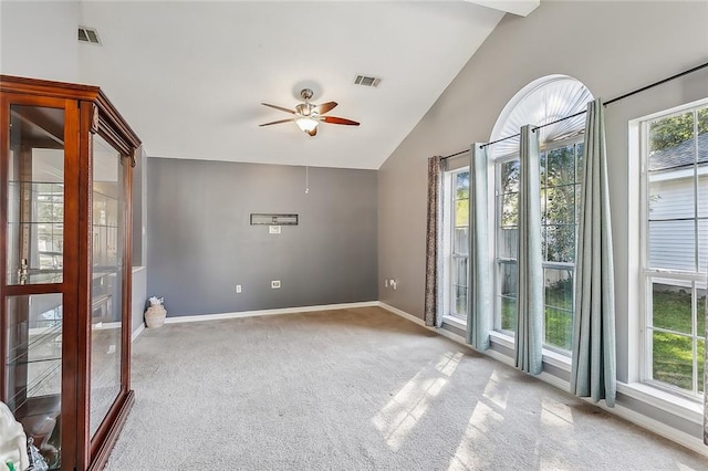 empty room featuring a healthy amount of sunlight, carpet, and vaulted ceiling