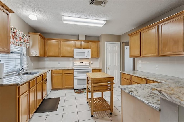 kitchen with sink, light tile patterned flooring, light stone counters, a textured ceiling, and white appliances