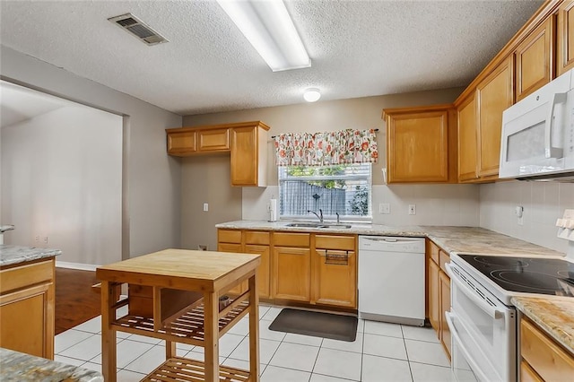 kitchen featuring sink, a textured ceiling, white appliances, and light tile patterned floors