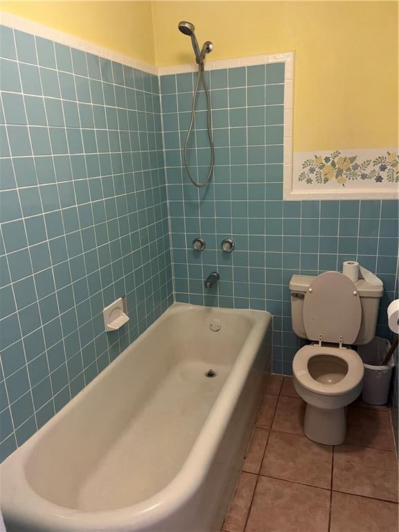 bathroom featuring tiled shower / bath, tile walls, toilet, and tile patterned flooring