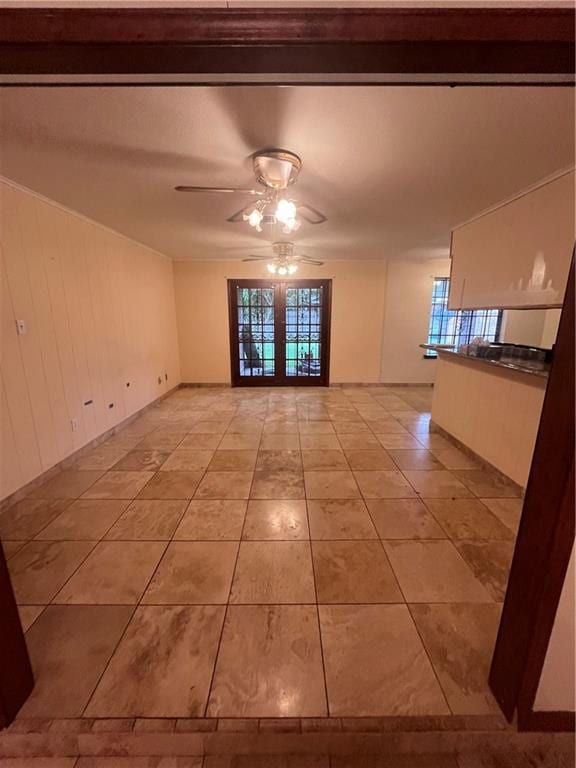 tiled empty room featuring french doors and ceiling fan