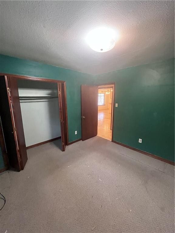 unfurnished bedroom featuring a textured ceiling, a closet, and carpet flooring